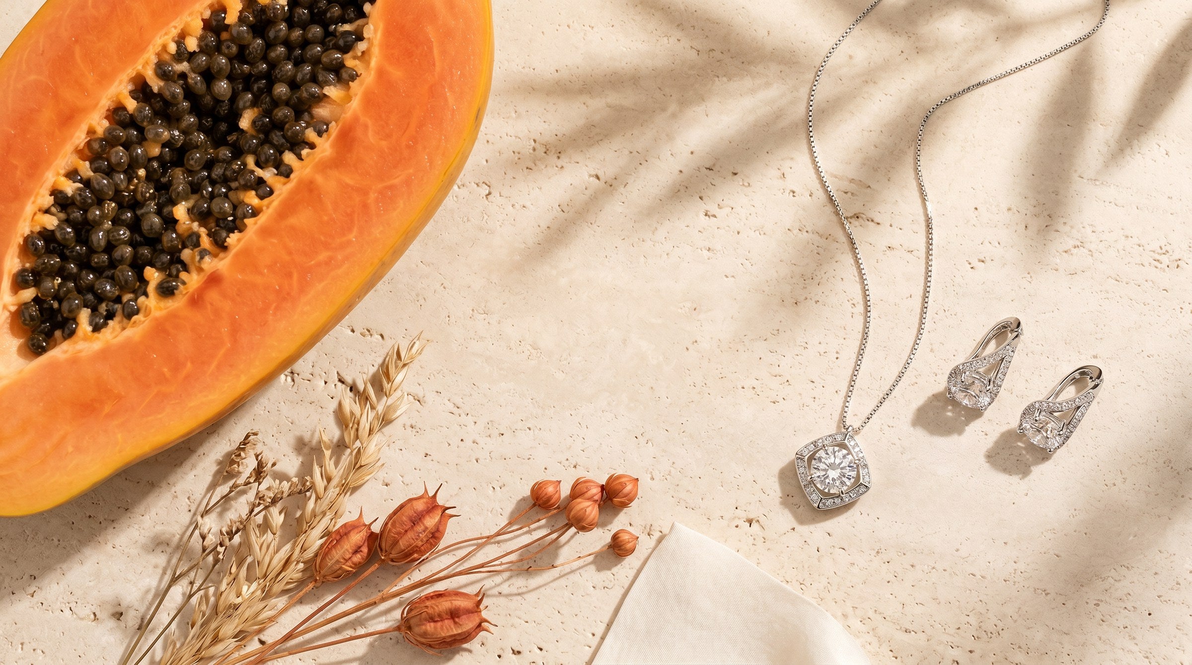 Alma y Sol jewellery on travertine with papaya and flowers